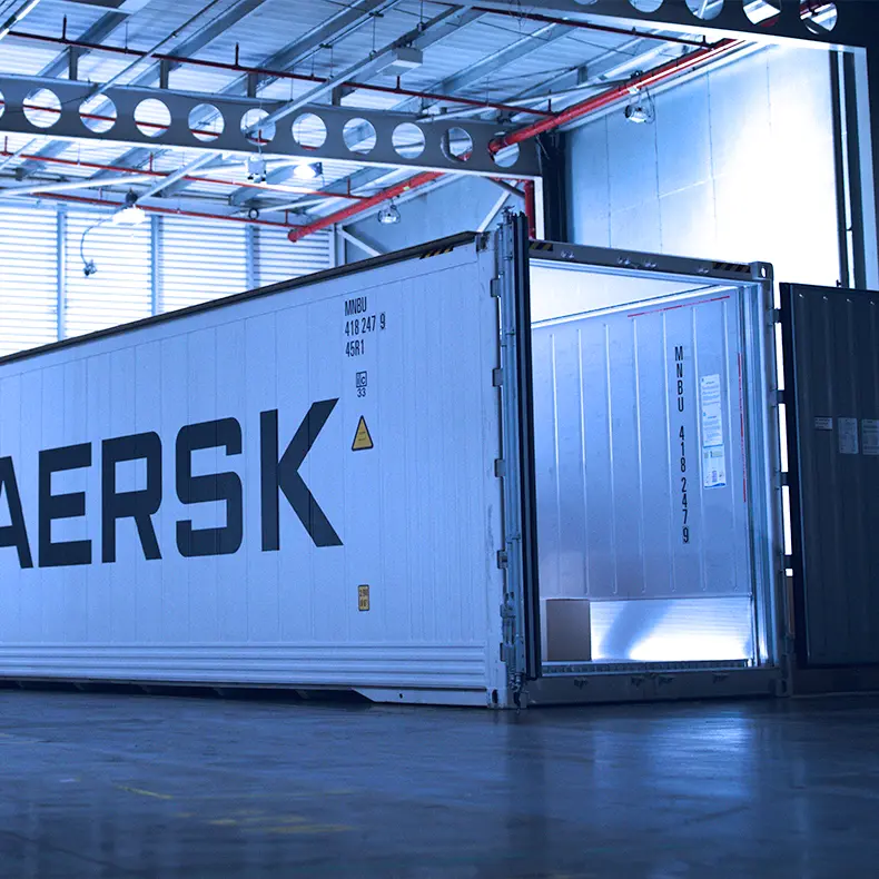 Maersk reefer container with its doors open inside a warehouse.