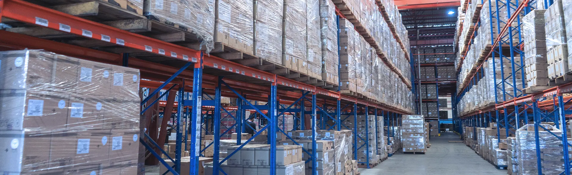 Warehouse aisle with wrapped pallets on high shelves.