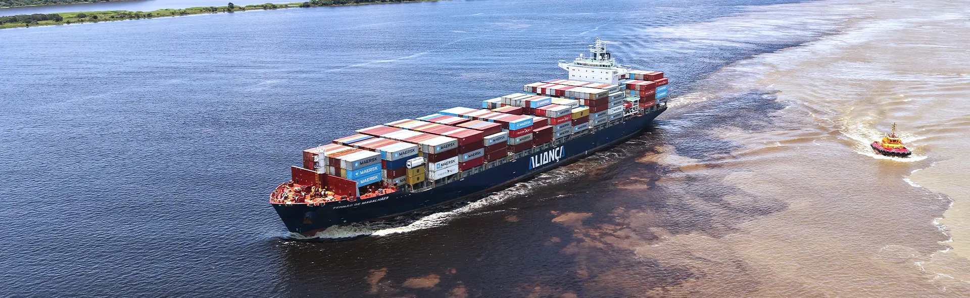 Aliança container ship sailing alongside a tugboat.